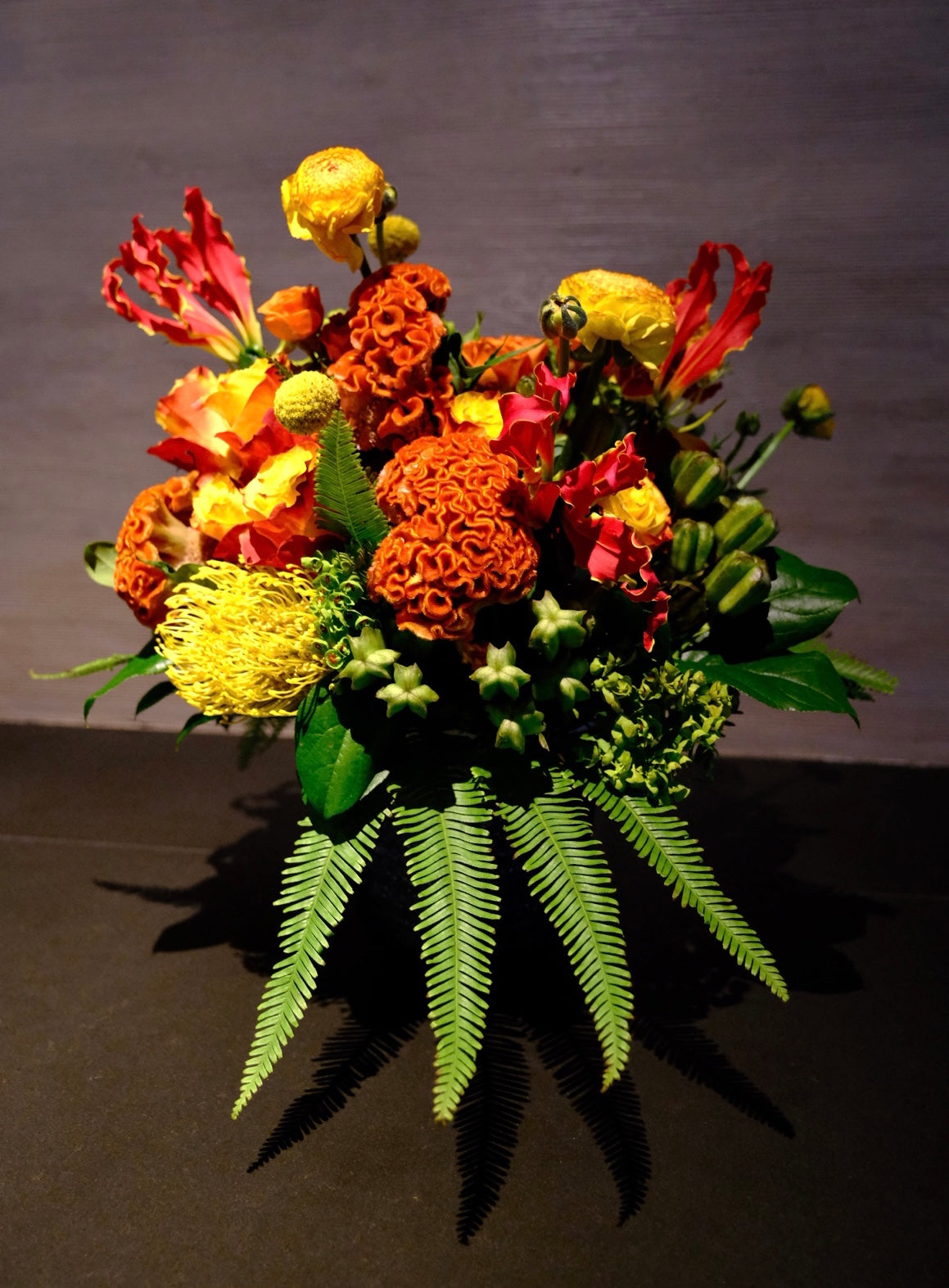 t is creative and high-end design. With four stems of Umbrella Fern, we created two dancers holding the most painterly flowers. A bundle of cockscomb blooms introduces movement. At the back two fire lilies protect the whole arrangement. 